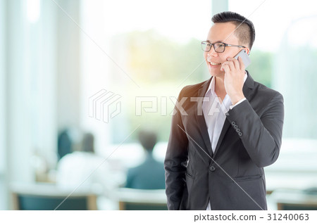 Handsome businessman using smart phone in office Handsome businessman using smart phone in office 31240063