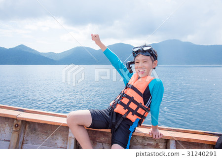 boy wearing life jacket sitting on the boat 31240291