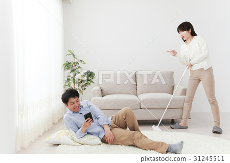 A woman wiping a floor, a man playing, an angry woman, a wiper, a room, a sofa 31245511