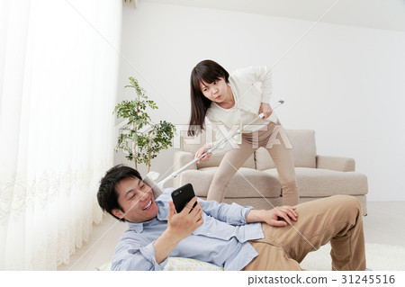 A woman wiping a floor, a man playing, an angry woman, a wiper, a room, a sofa 31245516
