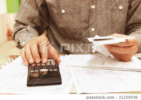 Asian young man using calculator. 31259556