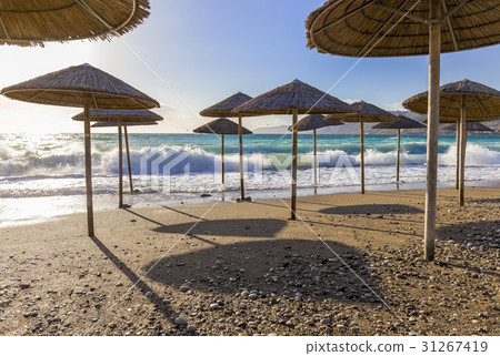 Umbreles on the sand beach with cloudy sky and sun 31267419