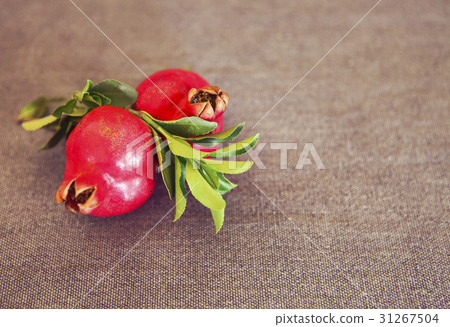 Two pomegranate fruits on textile background Two pomegranate fruits on textile background 31267504