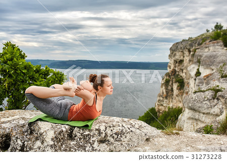 Sportive woman practicing yoga on the rock against Sportive woman practicing yoga on the rock against 31273228