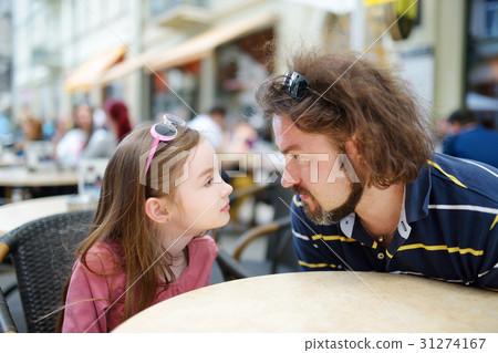 Funny girl with father having fun in outdoor cafe 31274167