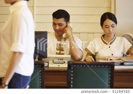 receptionists are making a phone call to confirm booking. 31284583