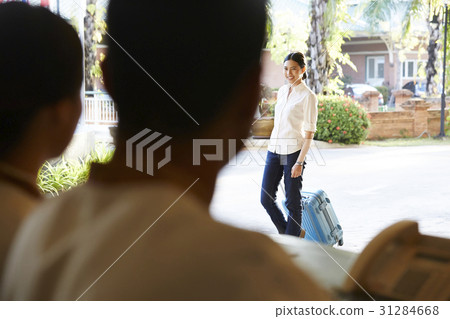 a guest is pulling her suitcase into the hotel. 31284668