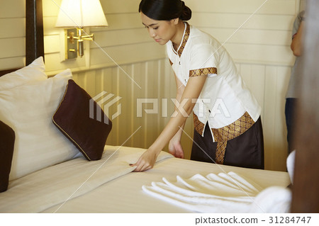 The young maid is changing the bedclothes in hotel room. 31284747