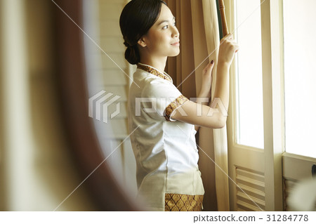 A female staff is adjusting curtains in the hotel room. 31284778