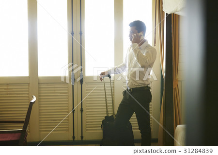 Businessman is holding his suitcase and answering the phone 31284839