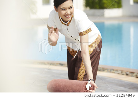 An Asian maid is waving hand to someone when working at resort. An Asian maid is waving hand to someone when working at resort. 31284949