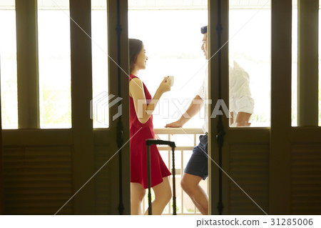 A photo of a happy couple talking at the balcony of the hotel room. 31285006