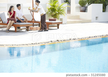 a photo of a couple sitting on a lounger, served drinks a photo of a couple sitting on a lounger, served drinks 31285080