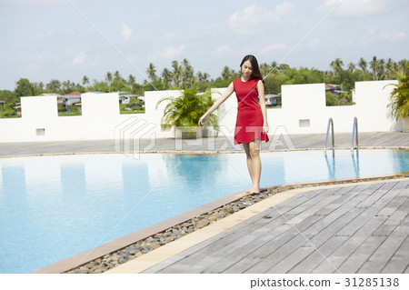 the girl is walking barefoot and thinking at a pool in resort 31285138