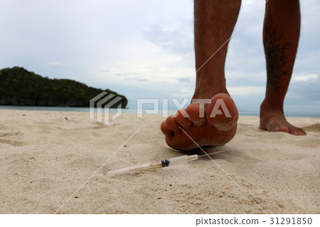 Foot step on injection needles on the beach. 31291850