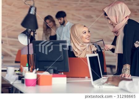 Two woman with hijab working on laptop in office. Two woman with hijab working on laptop in office. 31298665