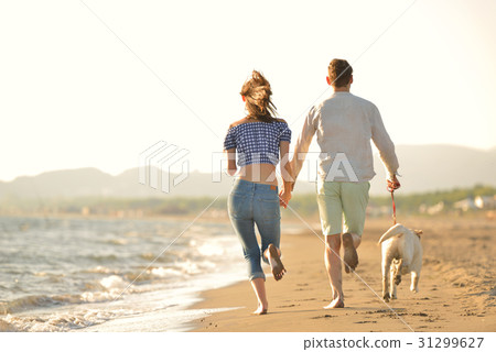 two young people running on the beach kissing and two young people running on the beach kissing and 31299627