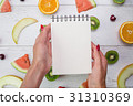 Top view of girl's hands, placed on white desktop 31310369