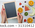 Top view of girl's hands, placed on white desktop 31310412