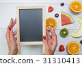 Top view of girl's hands, placed on white desktop 31310413