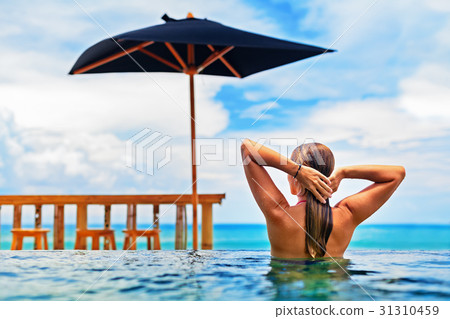 Woman swim in beach infinity pool with sea view 31310459