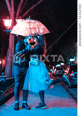 Guy and girl kissing under an umbrella Guy and girl kissing under an umbrella 31312563