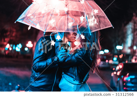 Guy and girl kissing under an umbrella Guy and girl kissing under an umbrella 31312566