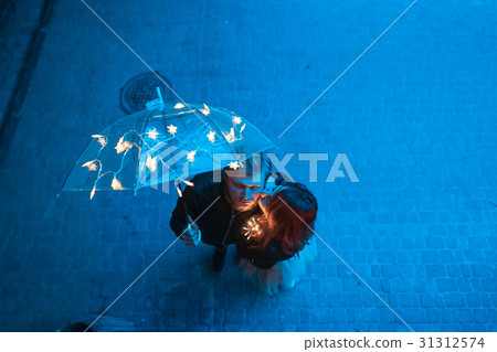 Guy and girl kissing under an umbrella Guy and girl kissing under an umbrella 31312574