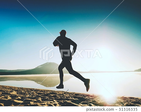 Tall young man runner running on sunrise seaside 31316335