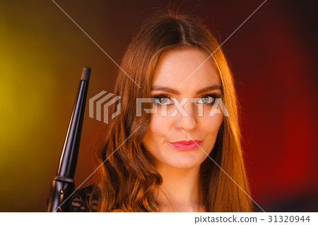 Happy woman curling her long brown hair Happy woman curling her long brown hair 31320944