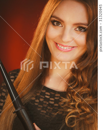 Happy woman curling her long brown hair Happy woman curling her long brown hair 31320945