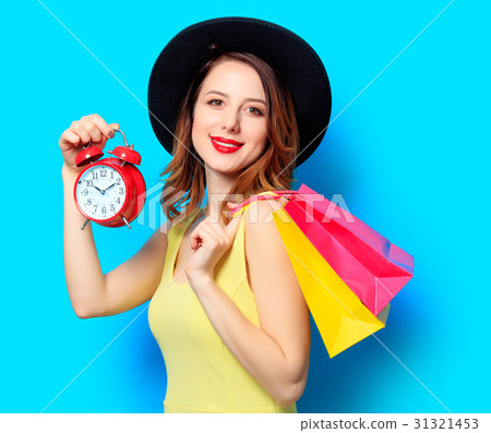 Woman with alarm clock and shopping bags Woman with alarm clock and shopping bags 31321453