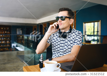 Young handsome hipster man in sunglases sitting in 31321512