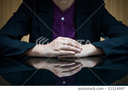 Businesswoman sitting at a desk and clasp her hand Businesswoman sitting at a desk and clasp her hand 31324997