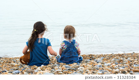 Tow little girls sitting on the beach 31328384