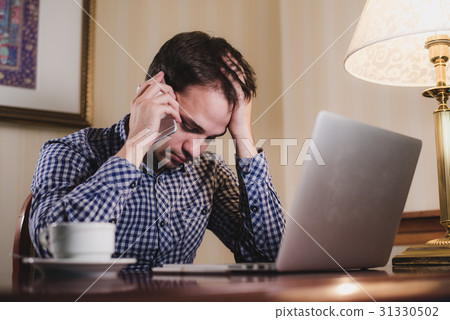 tired man with laptop and coffee having a work 31330502