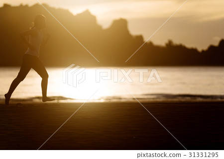Woman running on the beach at sunrise. 31331295