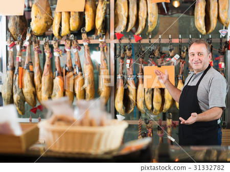 Senior man seller working with tasty Spanish jamon 31332782