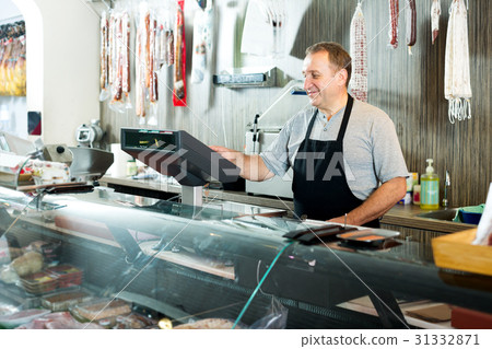 Male seller posing with wursts in butchery 31332871