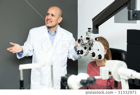 Male optician doing eye check up to girl 31332971