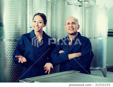 Portrait of cheerful two coworkers standing on wine factory Portrait of cheerful two coworkers standing on wine factory 31333155