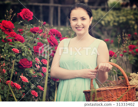 portrait of young female holding a basket near roses in outdoors 31333402