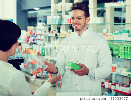 Man pharmacist helping customers in drug store 31333477