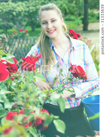 young woman holding a basket and standing in the park of roses 31333639