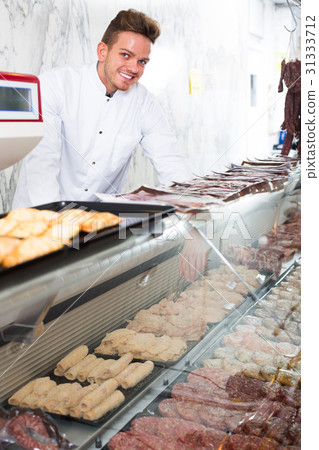 Happy young man seller working at meat market Happy young man seller working at meat market 31333712