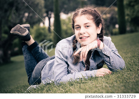 portrait of young female while lying in spring green garden 31333729