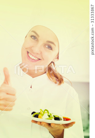portrait of young coosie woman showing salad at kitchen 31333867