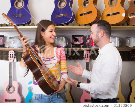 Young couple selecting acoustic guitar in shop 31333869