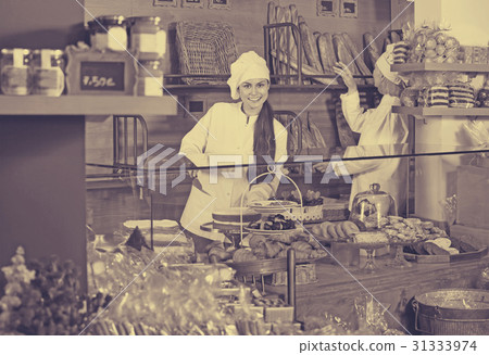 Cafe staff offering fancy and sponge cakes 31333974