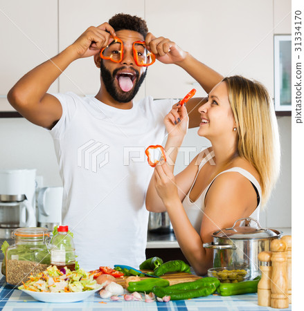Interracial couple cooking vegetables 31334170